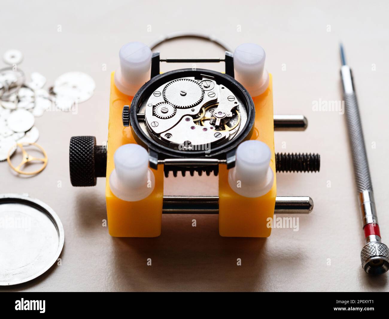 ouvrir la montre mécanique dans le support jaune fermer sur une table en bois dans l'atelier horloger Banque D'Images