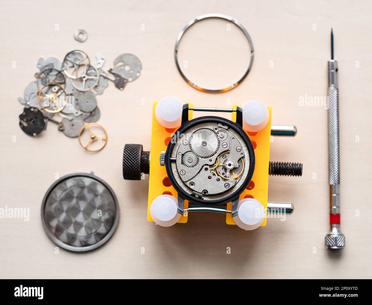au-dessus de la vue de la montre ouverte dans le support jaune sur la table en bois dans l'atelier horloger Banque D'Images