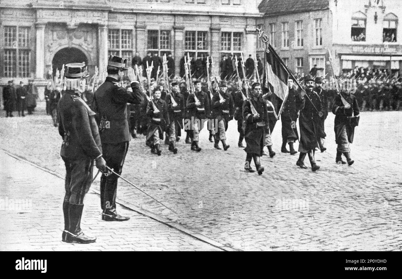 ''A Furnes, le roi des Belges, apres avoir decore de la croix de Léopold le drapeau de son 7E régiment de ligne et remis, au nom de la France, des croix de la Légion d'honneur a plusieurs officiels de ce corps d'élite, fait defiler devant les braves, Pendentif dix jours et dix nuits, ont repoussé les attaques de l'ennemi entre Nieuport et Dixmude, 1914. De "l'Album de la guerre 1914-1919: Volume I" [l'Illustration, Paris, 1926]. Banque D'Images