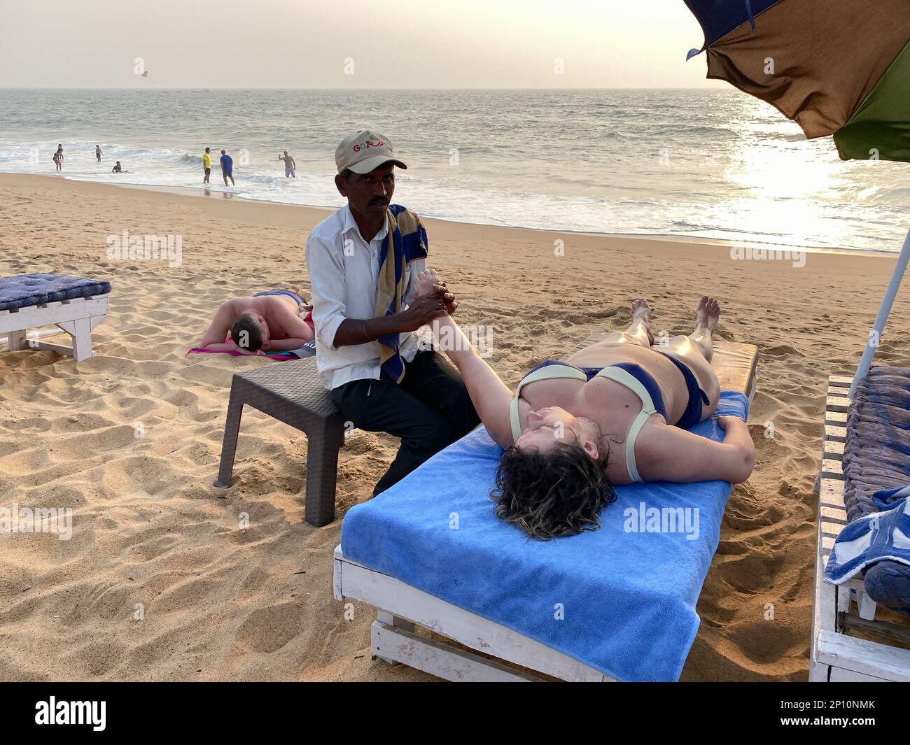 Candolim, Goa, Inde - janvier 2023 : un Indien qui donne un massage à une touriste femelle allongé sur un lit de plage à Goa. Banque D'Images
