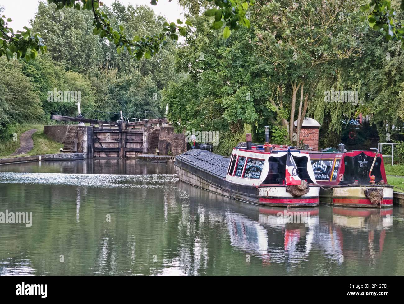 Une paire de bateaux anciens traditionnels colorés amarrés sous une écluse sur les canaux anglais Banque D'Images