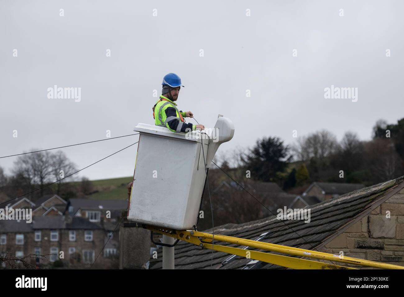 Entrepreneur en télécommunications avec équipement de sécurité approprié travaillant à partir d'un préparateur de cerisier pour installer une nouvelle ligne téléphonique domestique dans le West Yorkshire, au Royaume-Uni Banque D'Images
