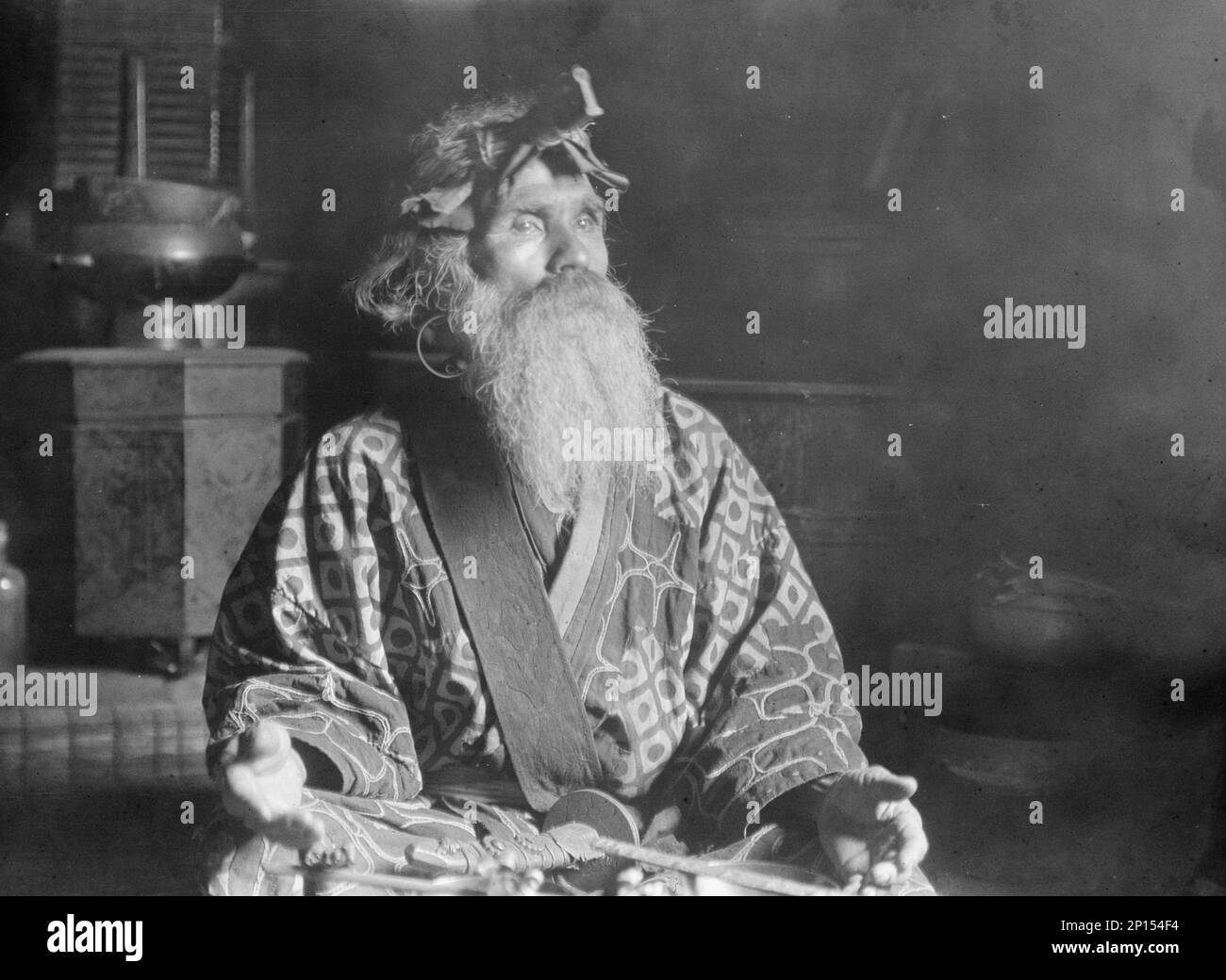 Chef Ainu portant une headaddress assise avec une épée sur ses genoux, 1908. Banque D'Images