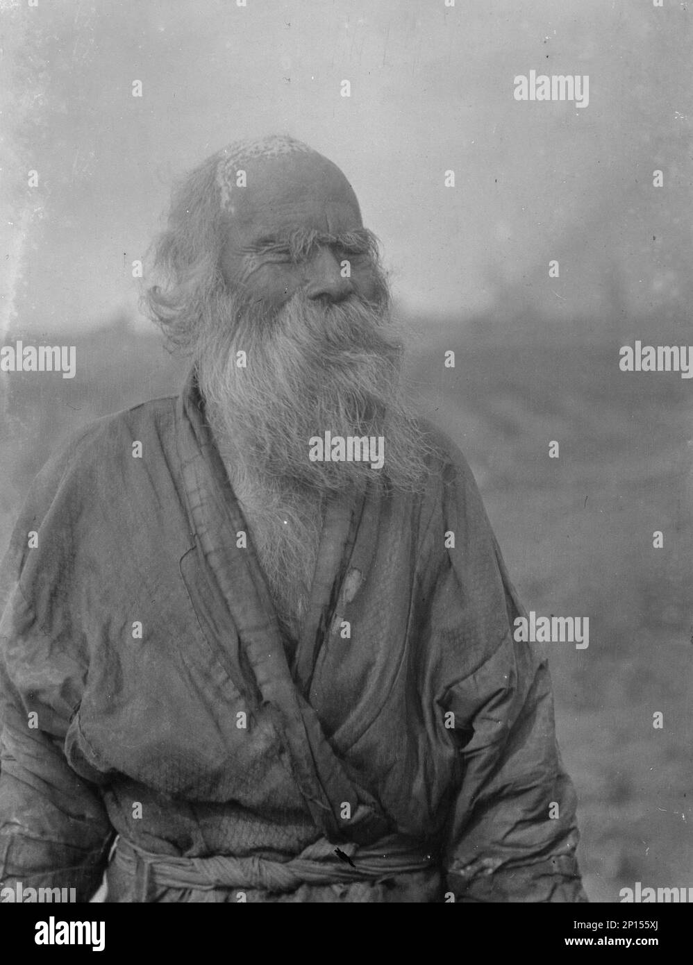 Ainu homme debout à l'extérieur, 1908. Banque D'Images