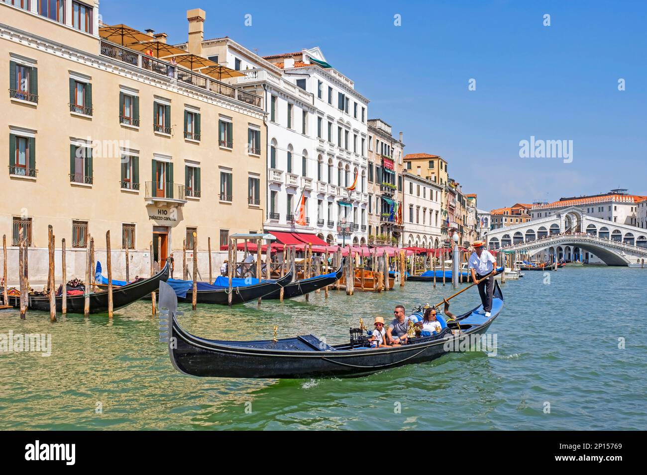 Pont Ponte di Rialto au-dessus du Grand Canal / Canal Grande et gondolier en gondole traditionnelle avec des touristes à Venise, Vénétie, Italie du Nord Banque D'Images
