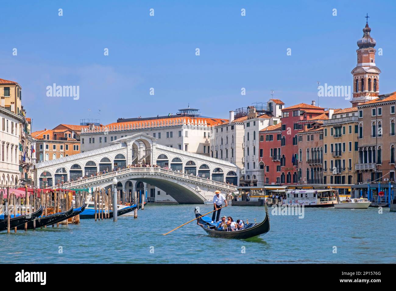 Pont Ponte di Rialto au-dessus du Grand Canal / Canal Grande et gondolier en gondole traditionnelle avec des touristes à Venise, Vénétie, Italie du Nord Banque D'Images