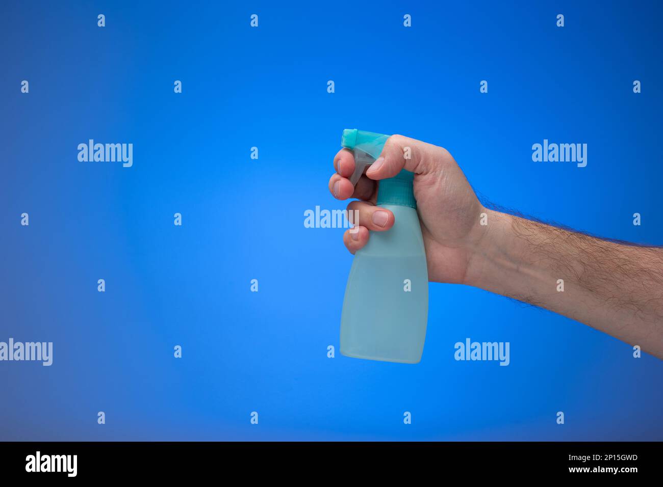 Buse de pulvérisateur d'eau bleu clair maintenue par une main mâle. Gros plan en studio isolé sur fond bleu. Banque D'Images