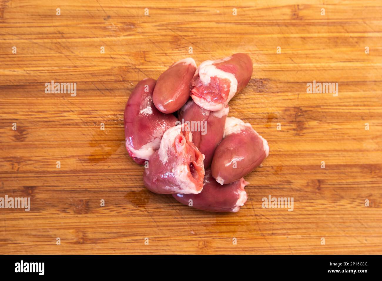 Cœurs de poulet cru regroupés sur une cuisine en bois vue du dessus. Banque D'Images