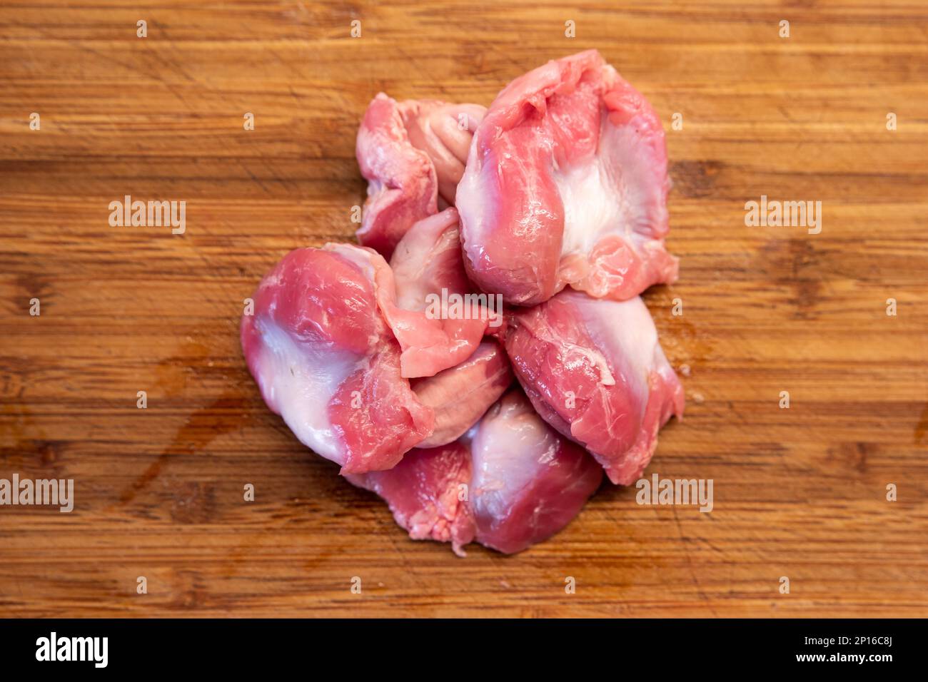 Stomachs de poulet cru regroupés sur un plan de cuisine en bois vue du dessus. Banque D'Images