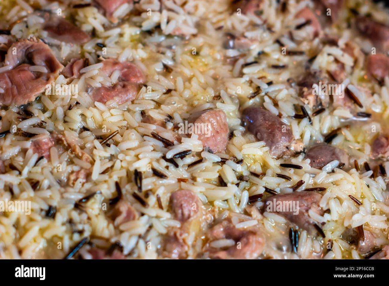 Pilaf de riz sauvage cuit avec coeurs de poulet et stomachs macro gros plan. Banque D'Images