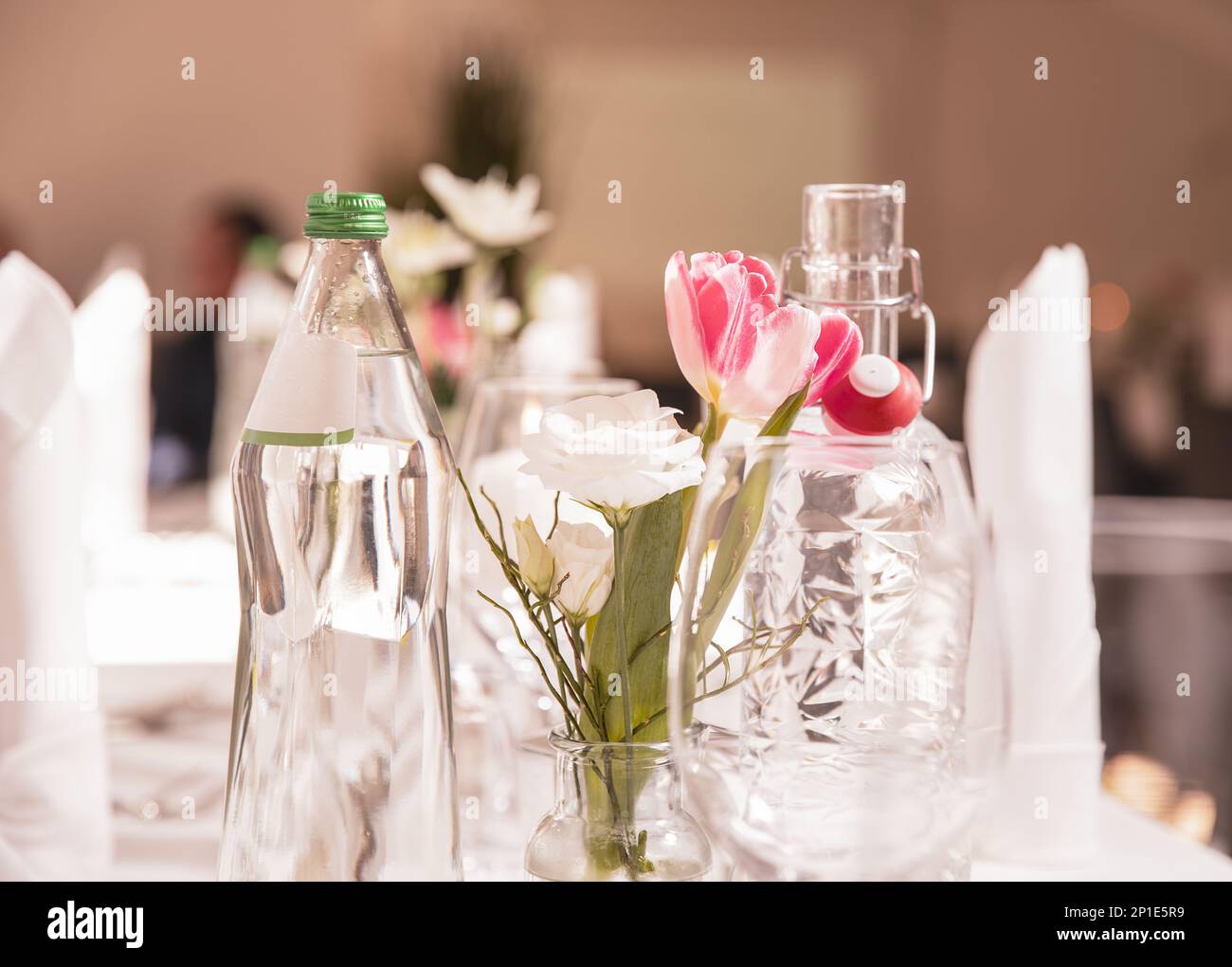 Table festive décorée dans un restaurant, verres à vin, vase, fleurs, bouteilles d'eau minérale, textiles, couverts sur une nappe blanche. Concept de mariage Banque D'Images