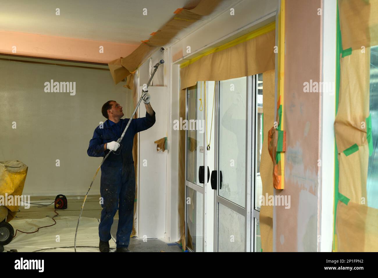 Un peintre applique une couche d'apprêt acrylique sur les murs intérieurs d'un bâtiment de rénovation près de Greymouth, Île du Sud, Nouvelle-Zélande Banque D'Images