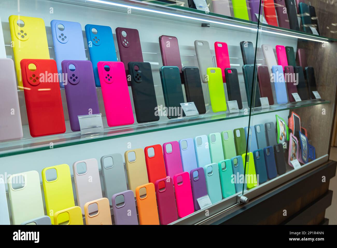 Vitrine avec étuis pour smartphones. Acheter des accessoires mobiles, présenter des étuis en plastique pour téléphones mobiles sur des étagères, présenter avec des smartphones Banque D'Images