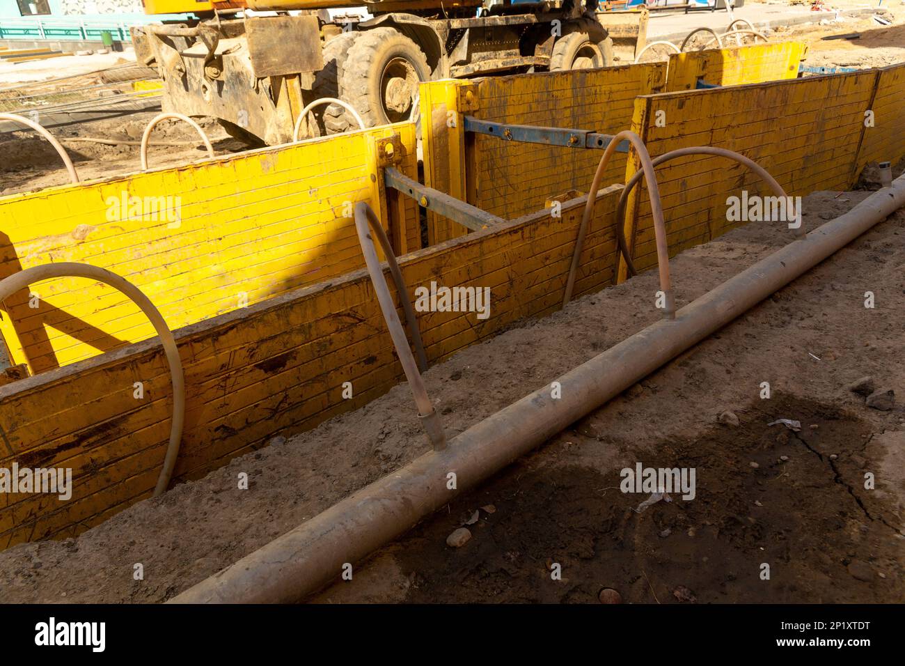 Pelle hydraulique remplissant une excavation profonde soutenue par une boîte de tranchée avec du gravier de pois de litière de tuyaux pendant l'installation du tuyau de drainage. Reconstruction technique Banque D'Images