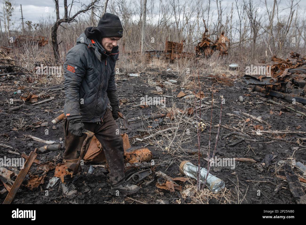 Des hommes locaux démantelent les restes de matériel militaire russe détruit et brûlé pour la ferraille, région de Kharkiv, Ukraine. En longeant les routes de la région de Kharkiv, plus vous vous rapprochez du Donbass, plus vous voyez de matériel militaire brûlé et cassé sur le bord de la route, dans les champs et les ceintures forestières. Dans l'une de ces ceintures forestières, nous avons vu une énorme quantité d'équipement russe brûlé. Quand nous nous sommes arrêtés pour prendre des photos, nous avons vu plusieurs hommes et adolescents systématiquement le faire passer. Ils le démontaient pour la ferraille, pour laquelle ils reçoivent 2 hryvnias par kilogramme. Ils ne peuvent pas collecter plus t Banque D'Images