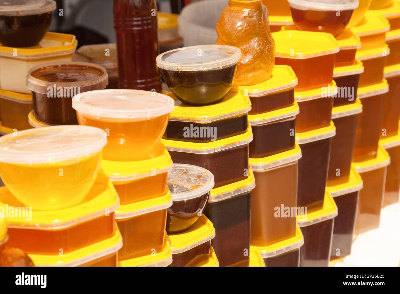 Des piles de conteneurs en plastique avec du miel à un marché alimentaire les agriculteurs. Beaucoup de pots de miel naturel doux de différents types et couleurs à vendre Banque D'Images