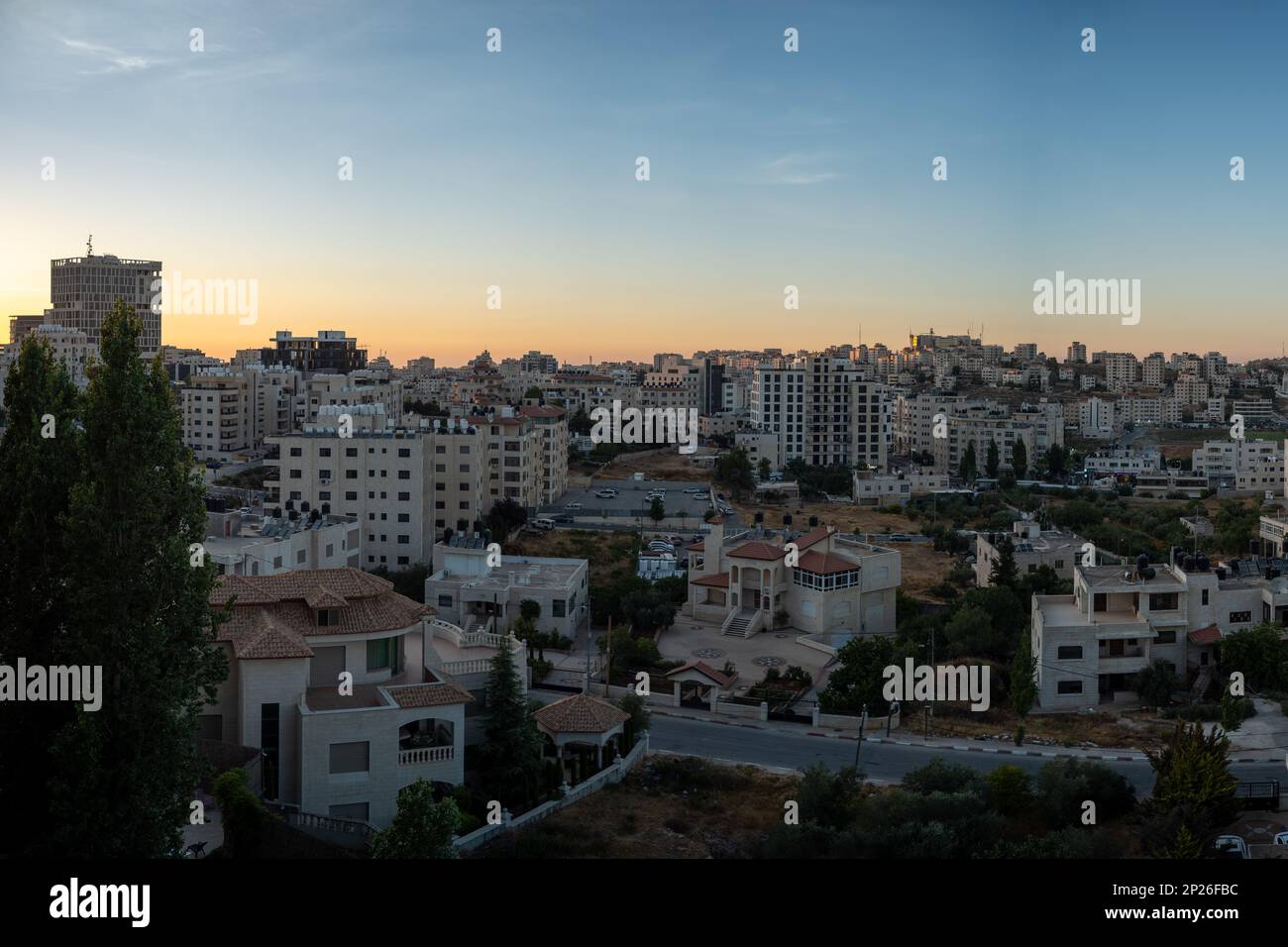 Ramallah, Ramallah et gouvernorat d'al-Bireh, Palestine, 8 juillet 2022: Ramallah Cityscape à Dusk avec de hauts bâtiments et des arbres contre le jaune foncé et Banque D'Images