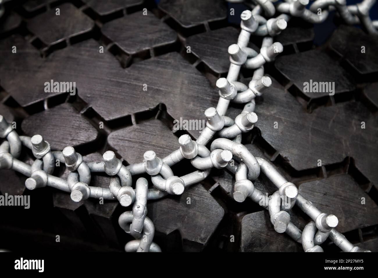 Nouvelles chaînes pour pneus cloutés propre close-up. Roue noire enveloppée dans des chaînes à neige d'argent Banque D'Images