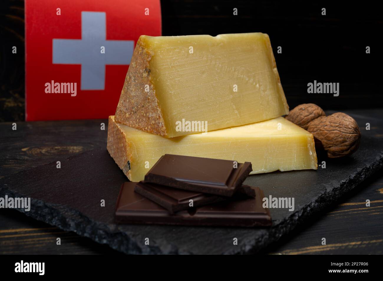 Fromage suisse de lait de vache moyen dur Gruyere, appenzeller, chocolat suisse foncé et drapeau suisse sur fond sombre Banque D'Images