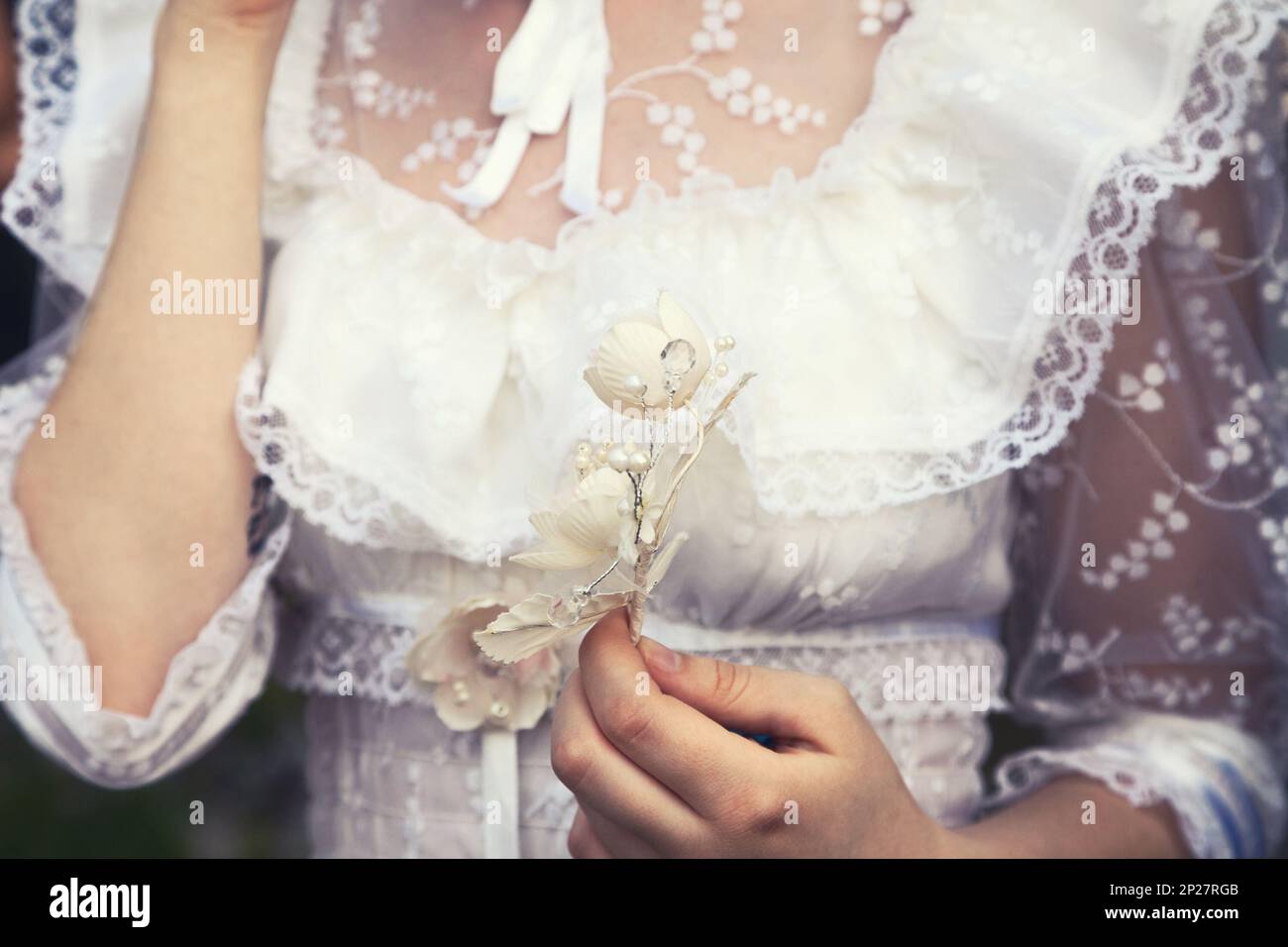 Jeune fille vierge dans une robe de dentelle blanche tenant une fleur. Tendre femme délicate à un mariage Banque D'Images