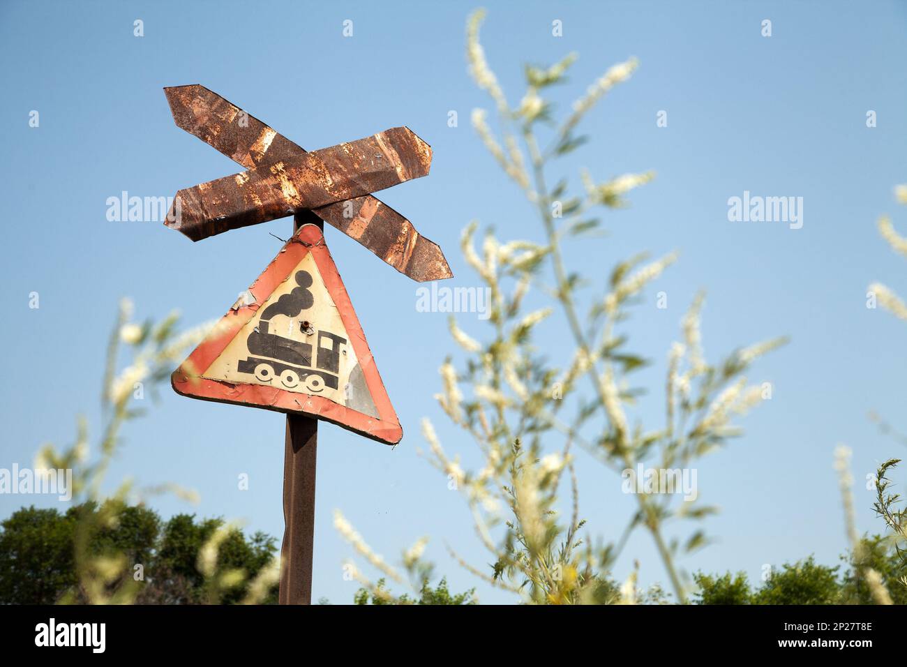 Très vieux rusty road sign avec un train photo - railroad crossing. Triangle patiné rouge signe de la circulation contre le ciel Banque D'Images