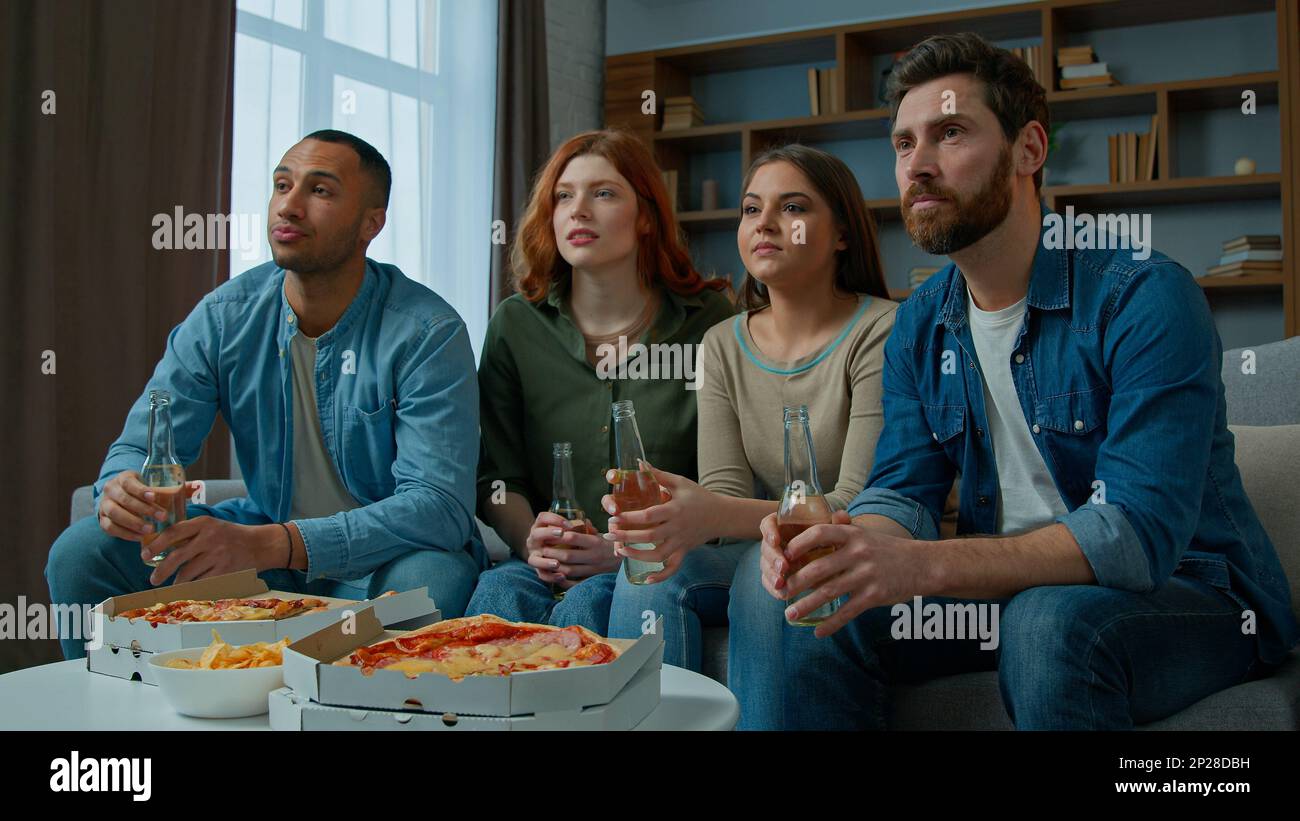 Quatre amis regardent la télévision avec de la bière et de la pizza à la maison diverses femmes multiethniques hommes fans de sport supporters regardant le championnat de football tv Banque D'Images