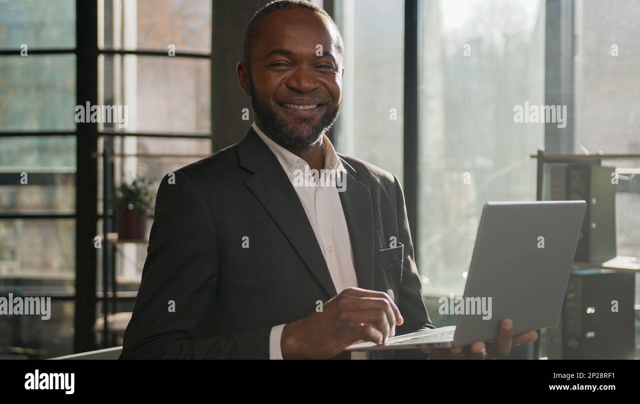Homme d'affaires senior homme ethnique afro-américain travailleur masculin développer un projet d'affaires en ligne sur ordinateur portable dactylographie sur clavier stand dans le soleil Banque D'Images