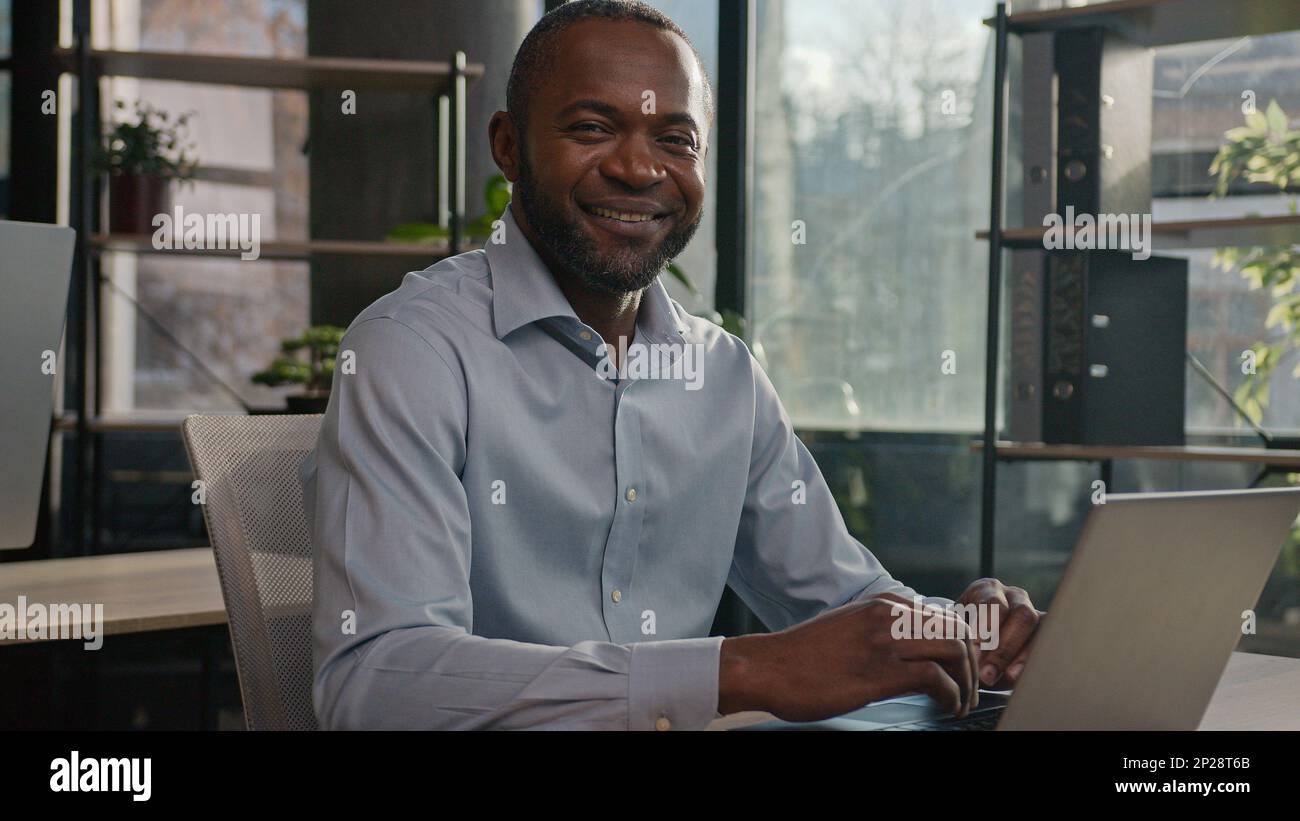 Professionnel d'âge moyen mature 40s ethnie afro-américain homme d'affaires senior employé de bureau assis à l'intérieur de recherche de données Internet sur un ordinateur portable Banque D'Images