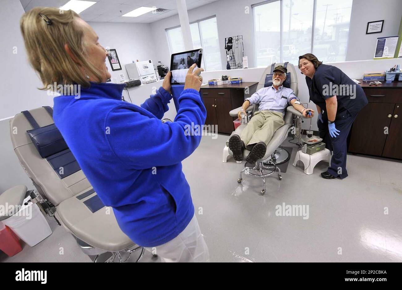 In this Wednesday, Sept. 23, 2015 photo, John Ball, of Charlottesville, Va., gets his picture taken by his wife, Alyson Ball, at left, with donor services technician Elaine Murman at the Life Serve Blood Center in Fort Dodge, Iowa. The donation completed Ball's quest to donate blood at least once in all 50 states. (Hans Madsen/The Messenger via AP) Banque D'Images