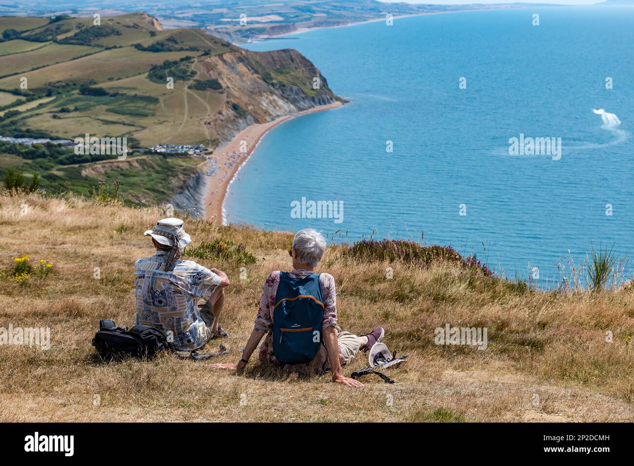 Couple de personnes âgées reposant sur le Cap d'Or avec vue sur la plage de Seatown, côte jurassique, Dorset, Angleterre, Royaume-Uni Banque D'Images