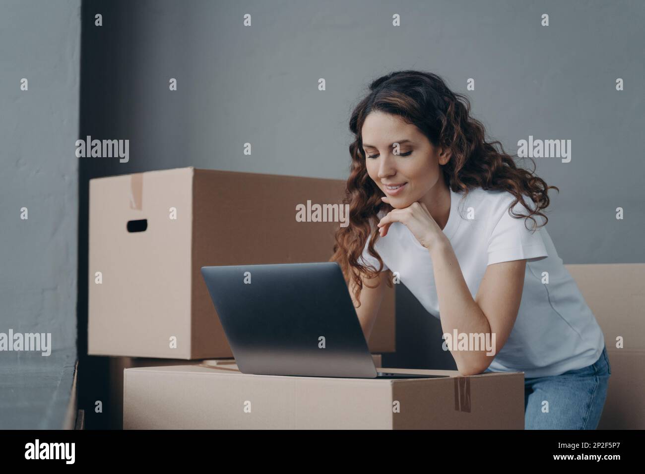 Jeune femme hispanique de service de livraison travaillant à l'ordinateur portable entouré de boîtes en carton. Femme d'affaires propriétaire de magasin en ligne préparant la commande du client Banque D'Images