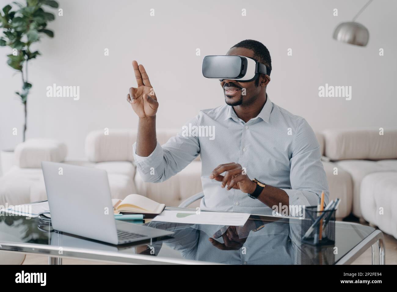 Un homme afro enthousiaste dans des lunettes vr sur le lieu de travail à la maison. L'homme d'affaires a une réunion virtuelle. Freelance travaille sur un projet de conception. Technologie sans fil moderne Banque D'Images