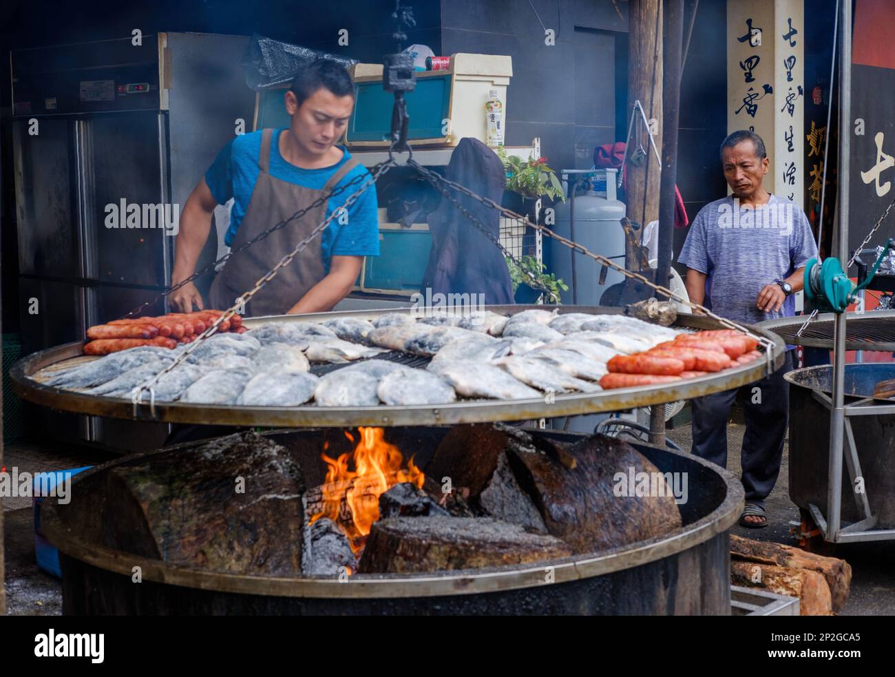 De jeunes hommes autochtones préparent une cuisine traditionnelle sur un grand barbecue Banque D'Images