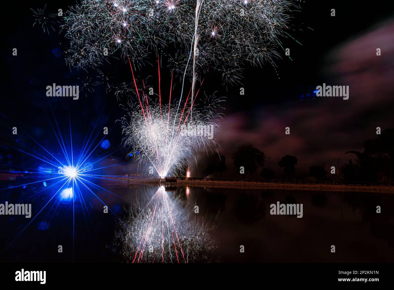 joyeuses fêtes du nouvel an la veille du nouvel an feux d'artifice colorés à la pyrotechnique dans le ciel noir foncé avec l'image de la fusée de couleur réflecte Banque D'Images