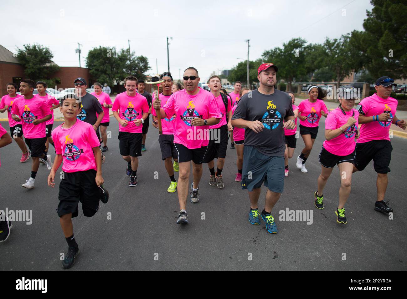 Texas Department of Public Safety Trooper Oscar Villarreal, center, carries the Special Olympics "Flame Of Hope" along with law enforcement officers from the Odessa area and the Ector Junior High cross country team as they start off the West Texas leg of the Law Enforcement Touch Run Wednesday morning, May 20, 2015, in Odessa, Texas.(Courtney Sacco/Odessa American via AP) Banque D'Images