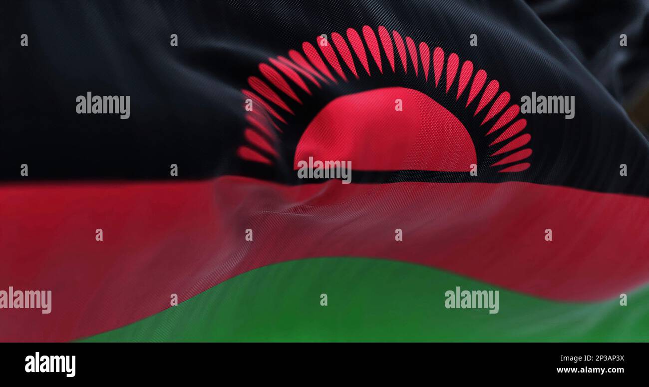 Vue rapprochée du drapeau national du Malawi. Tricolore de noir, rouge, rayures vertes, soleil levant rouge avec 29 rayons sur noir. Arrière-plan texturé en tissu. Banque D'Images
