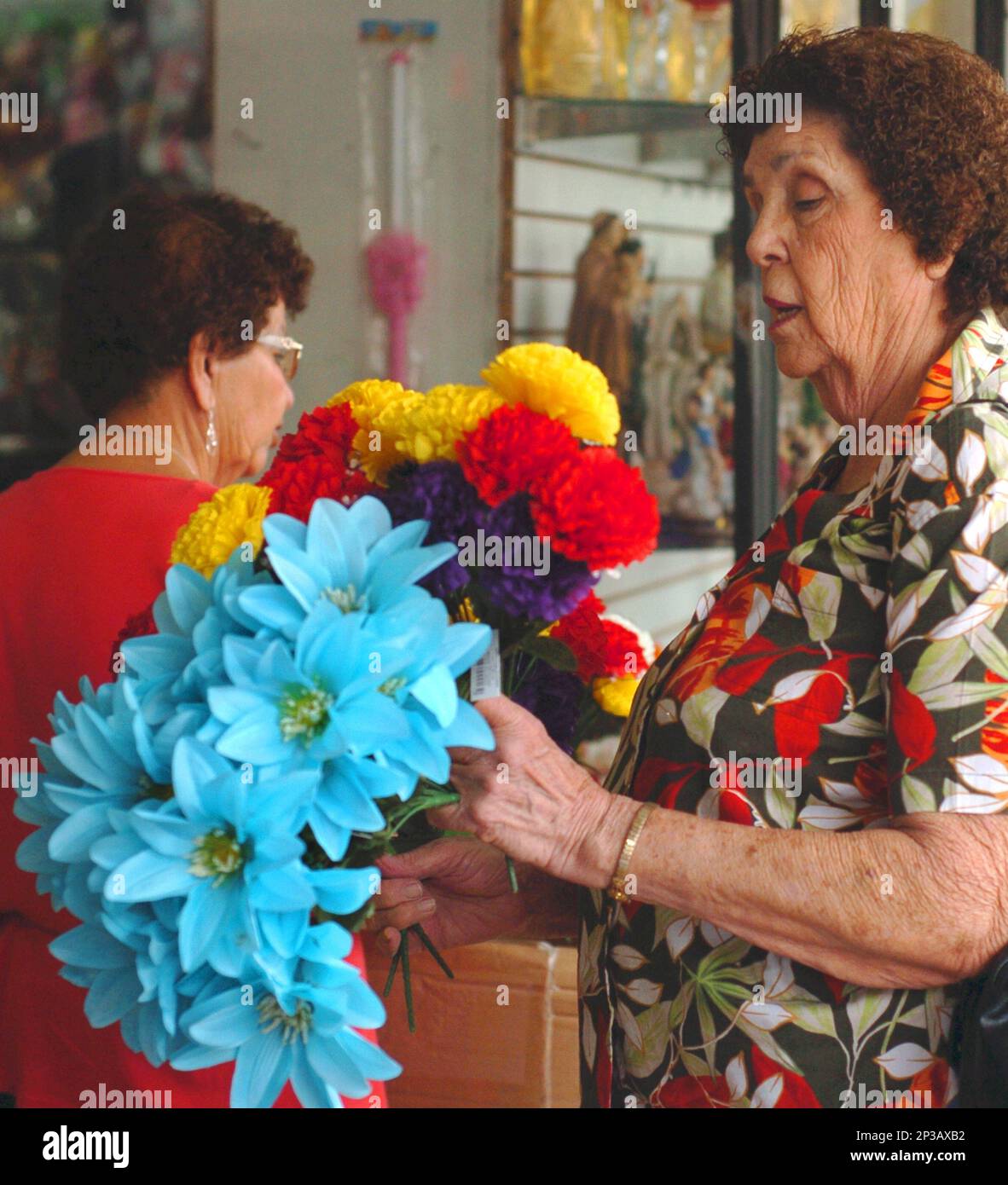 Sisters shop for artificial flowers Wednesday, March 18, 2015 under an awning at Gigante gift store along Elizabeth Street in Brownsville, Texas, to place at their loved ones tomb at the city cemetery. (AP Photo/The Brownsville Herald, ) Banque D'Images