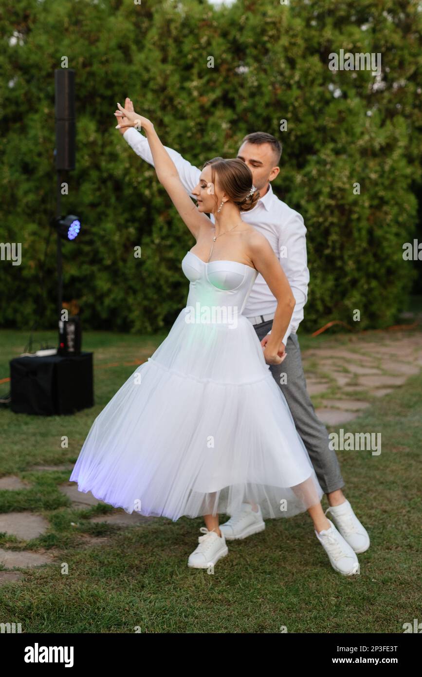 la première danse du marié et de la mariée dans une robe de mariage courte  sur un pré vert Photo Stock - Alamy