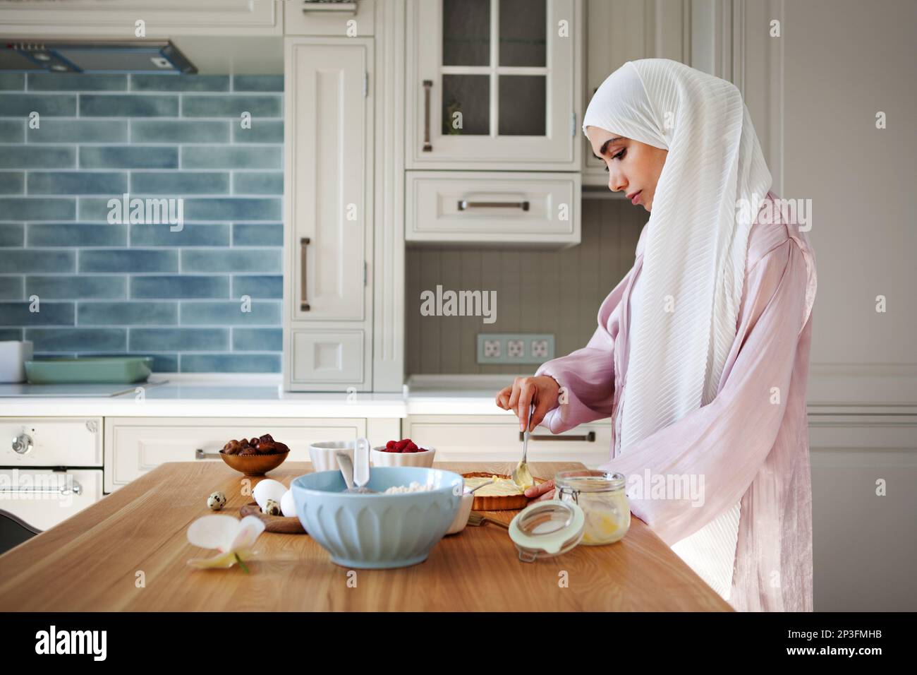 Jeune femme musulmane dans le hijab préparant le petit déjeuner dans la cuisine à la maison. Femme arabe pâtisserie Banque D'Images