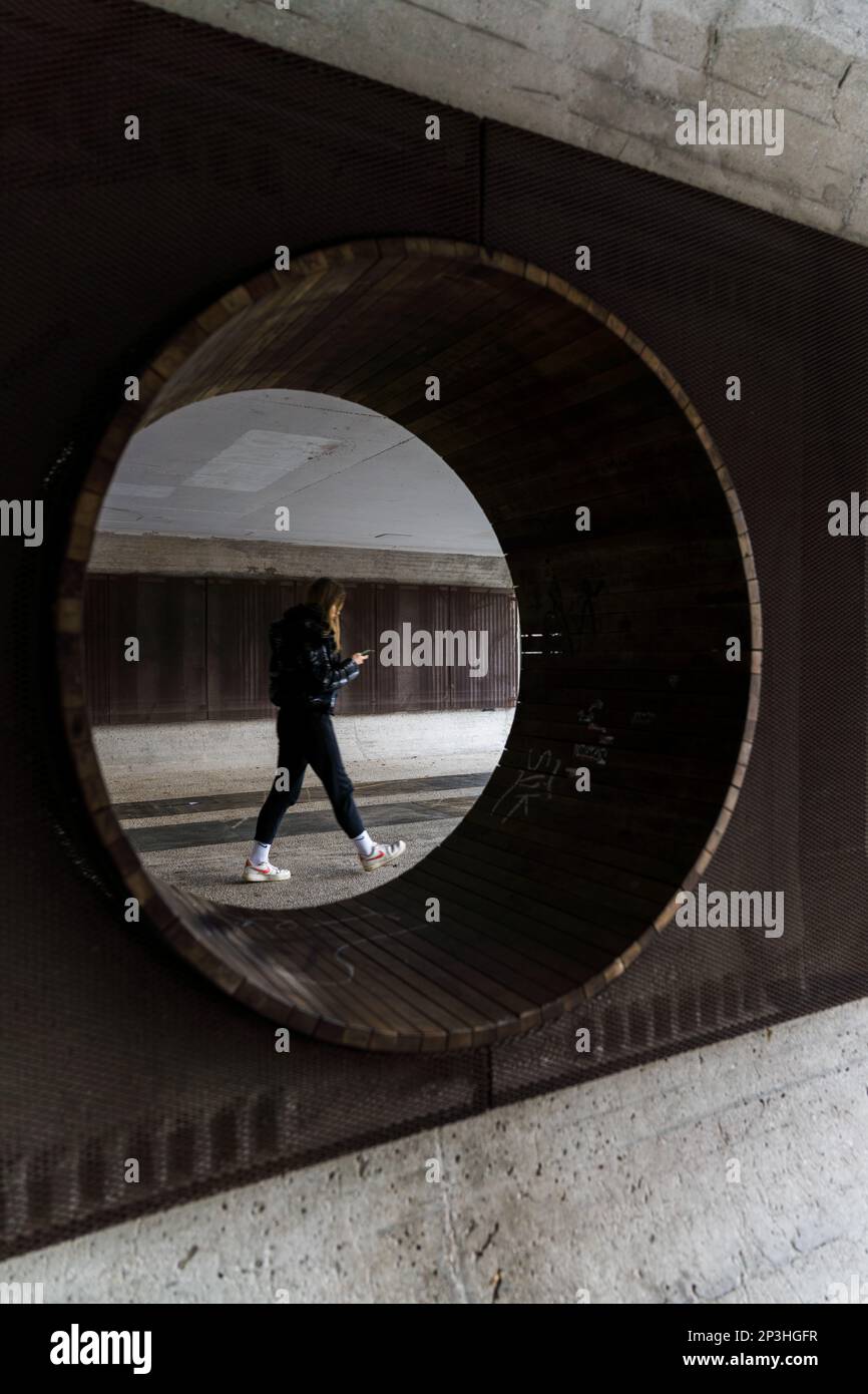 12 27 2022, Ljubljana, Slovénie: Une femme regardant son smartphone dans des baskets blanches marchant dans un tunnel vers la lumière, prise par un rou Banque D'Images 12 27 2022, Ljubljana, Slovénie: Une femme regardant son smartphone dans des baskets blanches marchant dans un tunnel vers la lumière, prise par un rou Banque D'Images