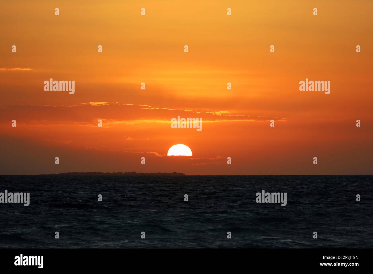 Lever du soleil sur une plage, le soleil orange brille à travers les nuages et se reflète dans les vagues sombres. Fond marin le matin pour un voyage romantique Banque D'Images