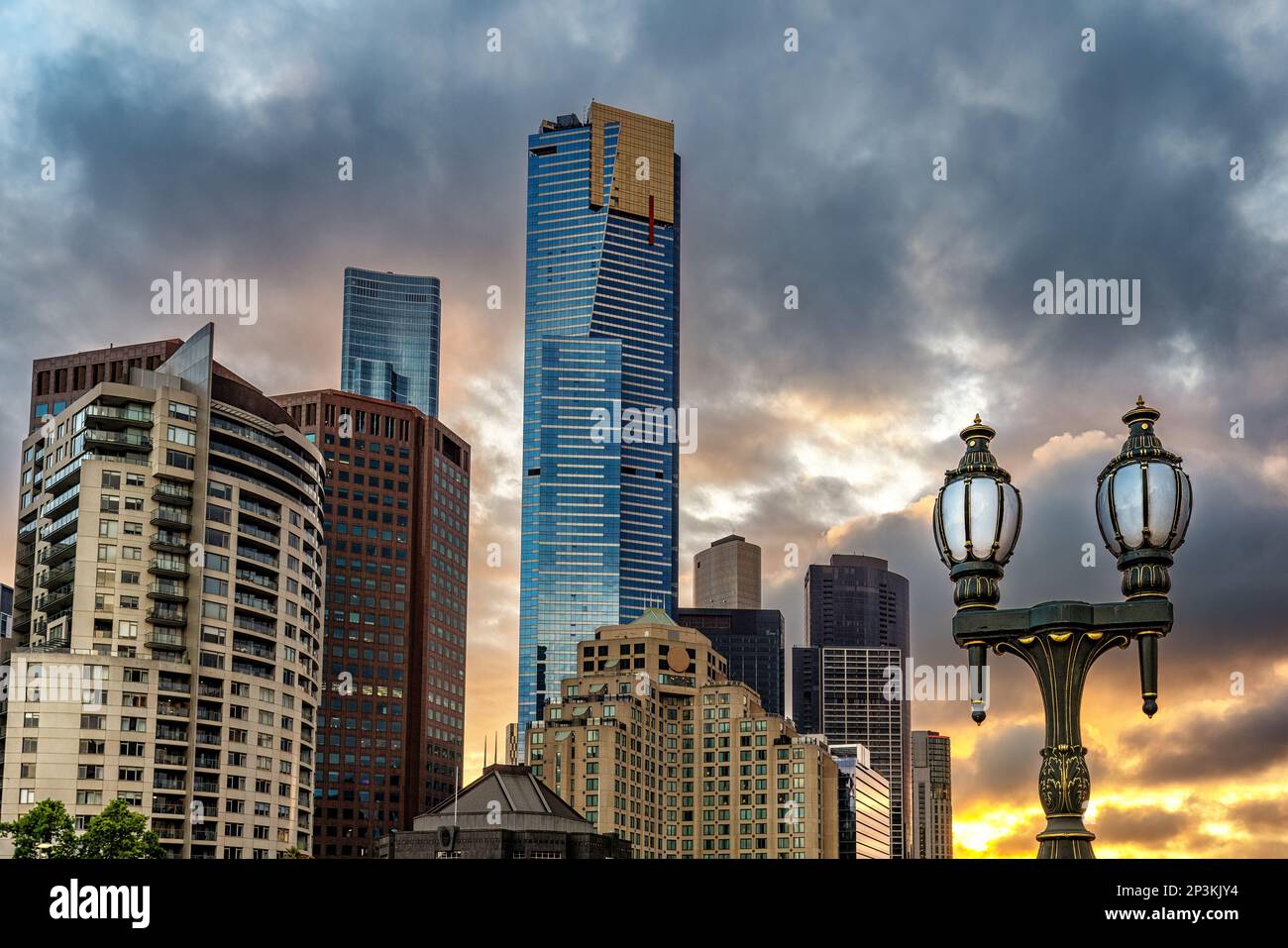 Le soleil se couche sur la ville de Melbourne. Un lampadaire à l'ancienne au premier plan avec un paysage urbain moderne en arrière-plan. Banque D'Images