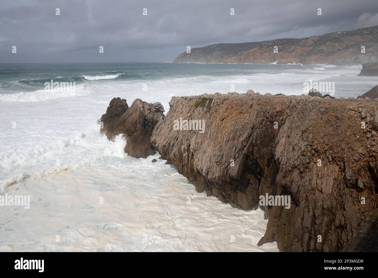 Vagues de l'océan Atlantique orageux s'écrasant sur des rochers sous forte do Guincho en regardant vers le nord jusqu'à la pointe de Ponta do Rebolo Banque D'Images