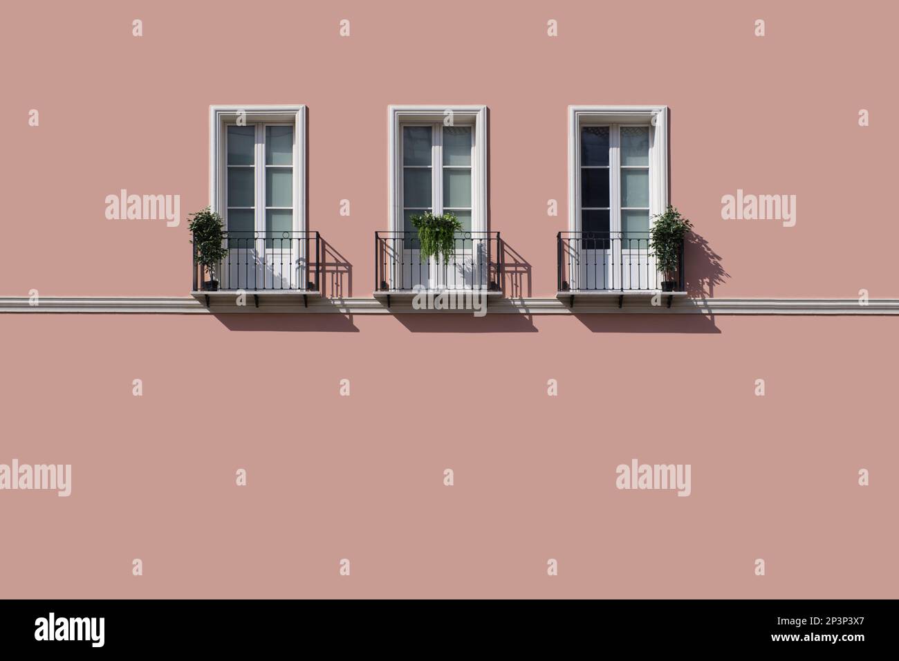 Trois fenêtres avec balcon sur un grand mur rose vide Banque D'Images