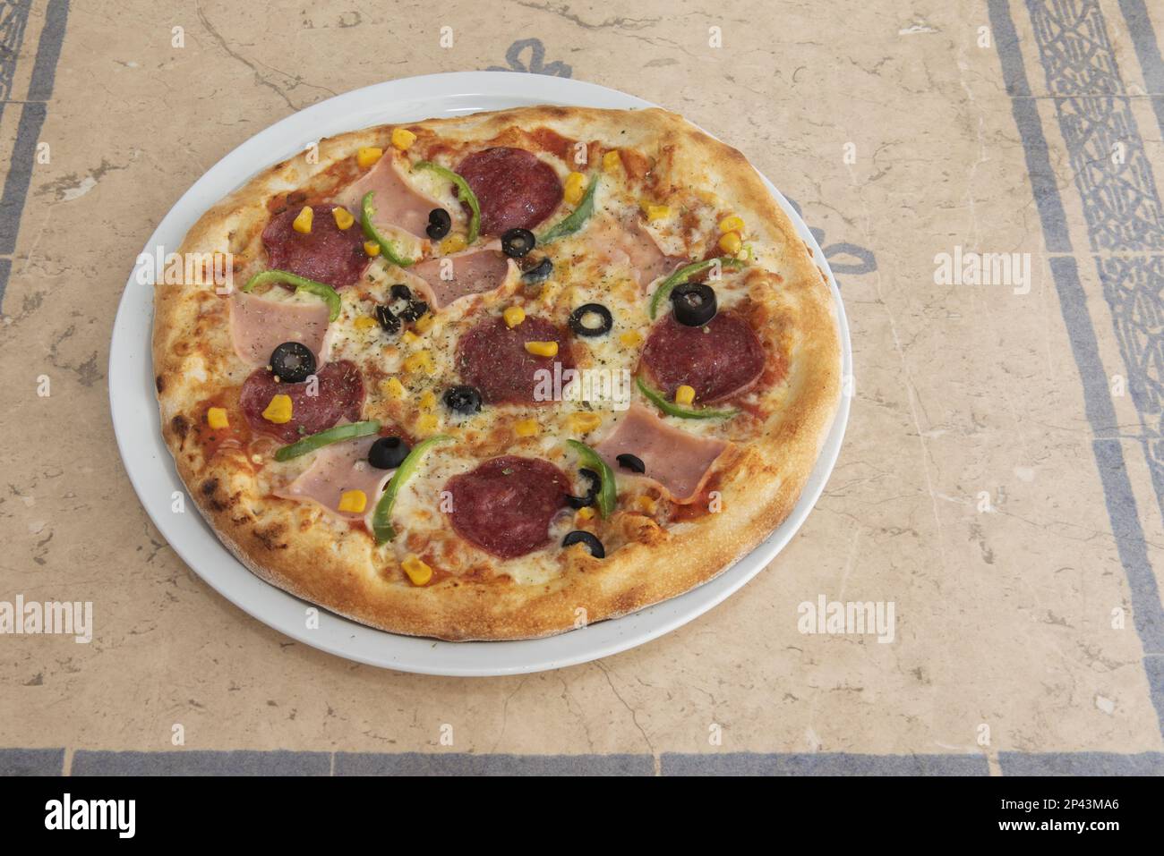 Une pizza au pepperoni aux poivrons, au jambon et au maïs sucré aux