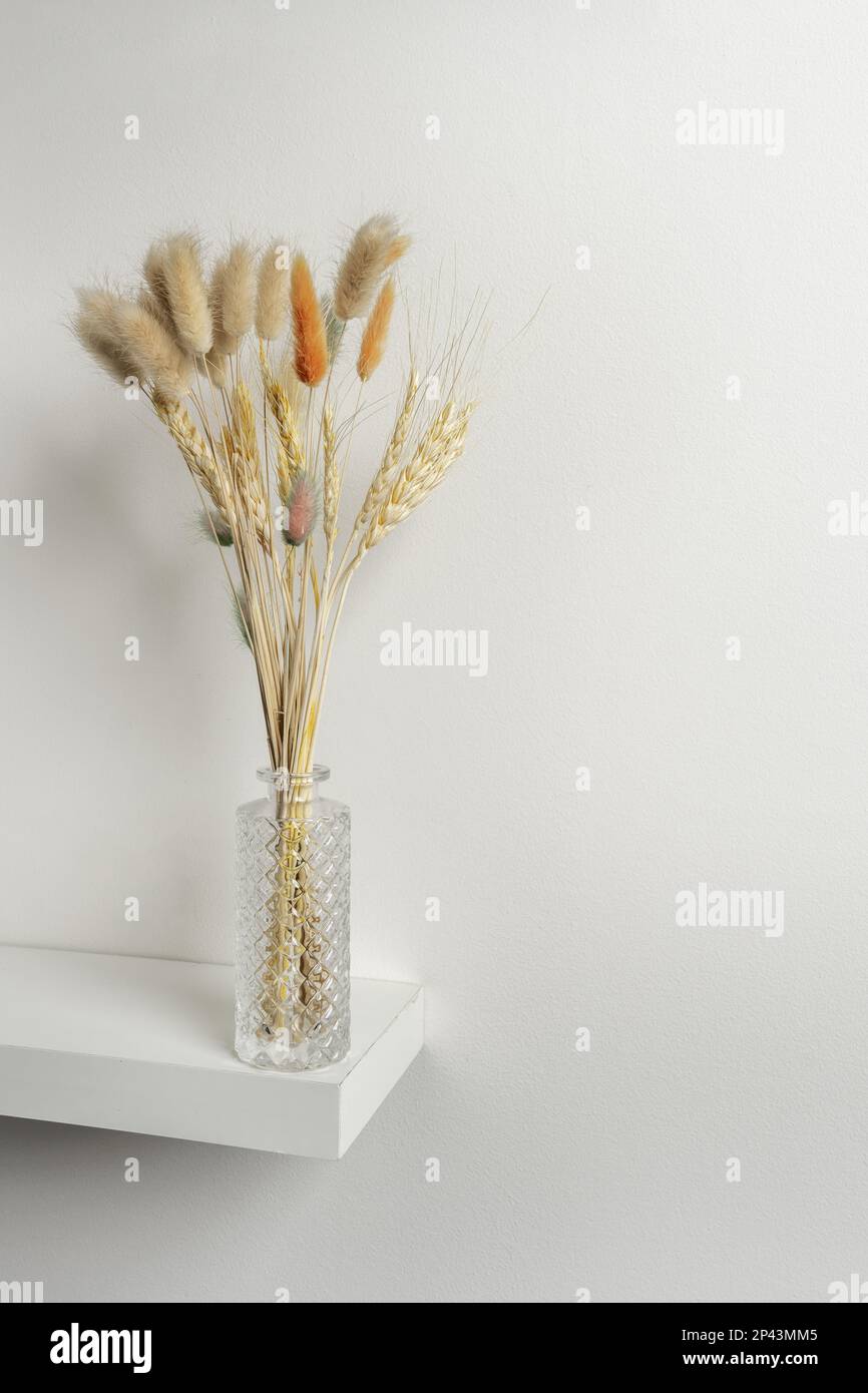 Petit vase en verre sculpté avec des pointes et des branches de plantes séchées, certains colorés Banque D'Images