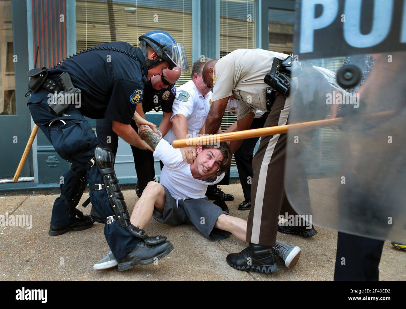 Police officers arrest a man who refused to leave when police in riot gear cleared the area of S. Florissant Road and Church Street in downtown Ferguson, Mo., on Monday, Aug. 11, 2014. Hundreds of people marched in front of the Ferguson police station against Saturday's police shooting of Michael Brown. (AP Photo/St. Louis Post-Dispatch, Robert Cohen) Banque D'Images