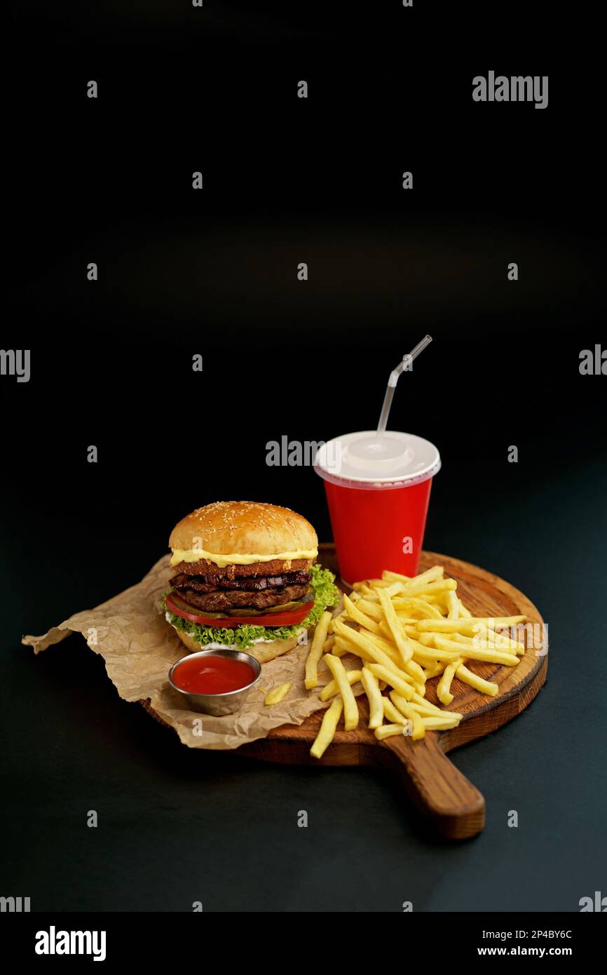 Délicieux double hamburger maison avec du bœuf, de la laitue, du bacon, de la tomate et du fromage sur fond de bois. Banque D'Images
