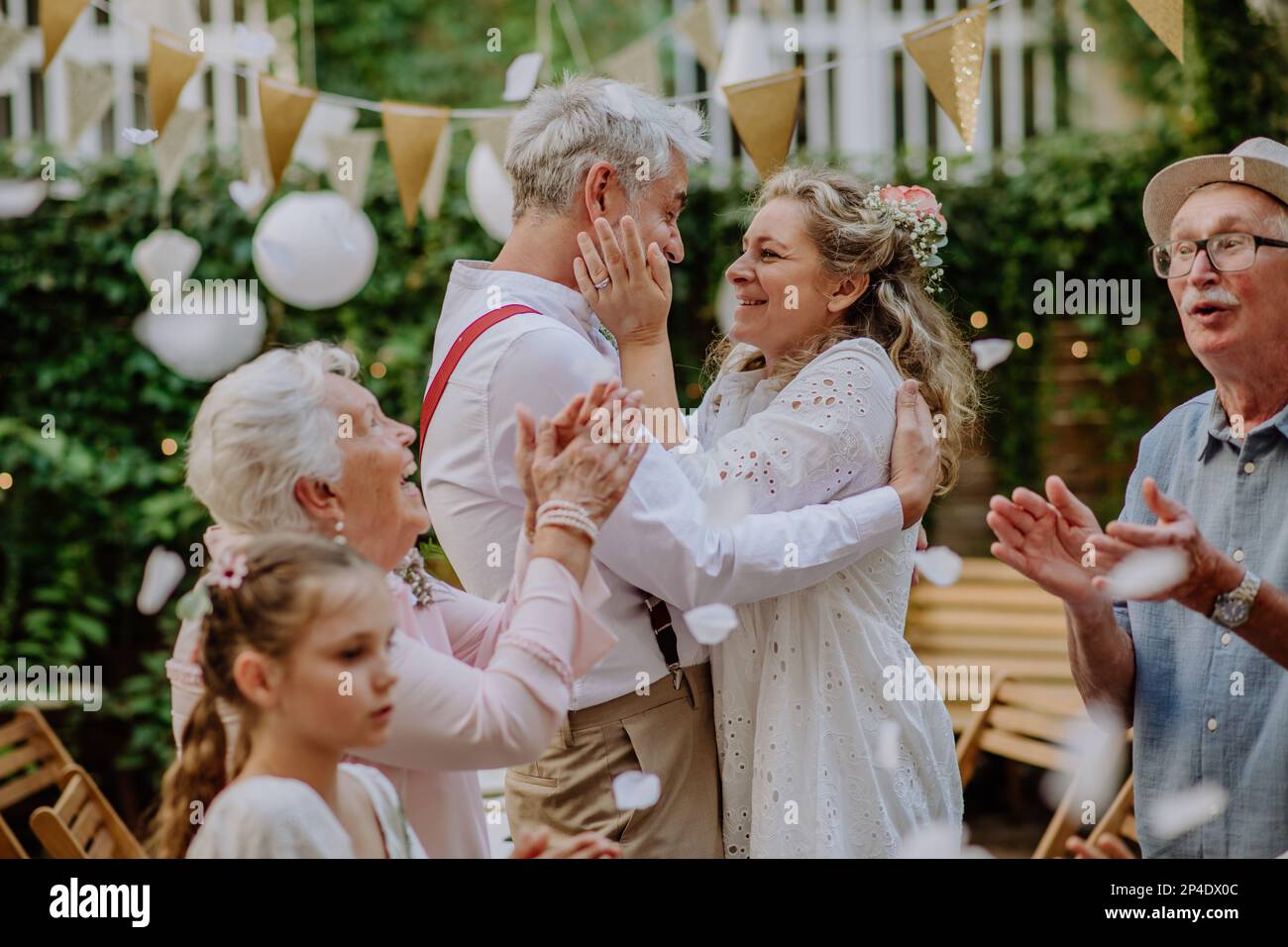 Mariée et marié matures célébrant le mariage avec leur famille, à l'extérieur de l'arrière-cour. Banque D'Images