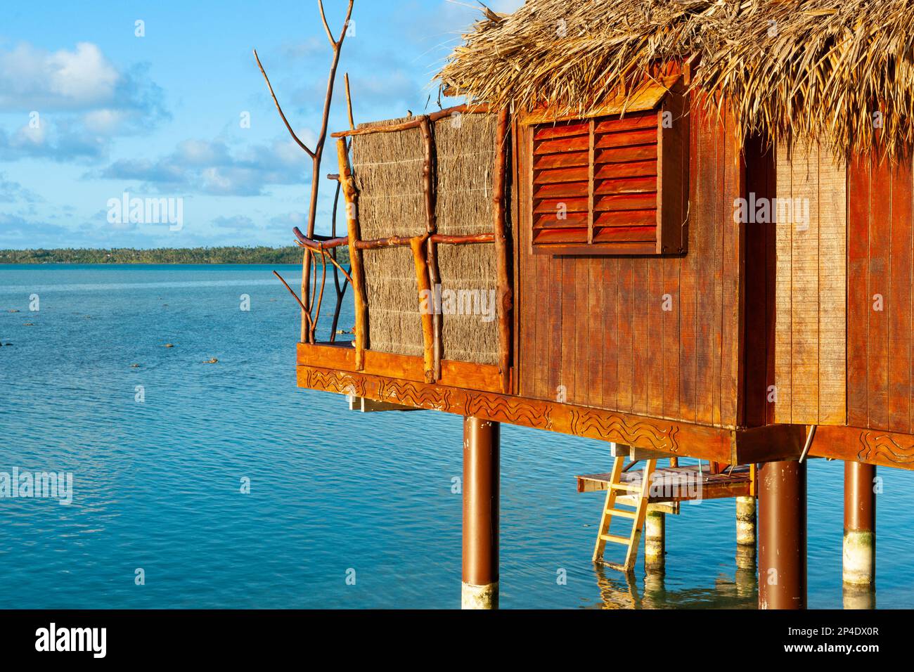 Chalet rustique idyllique avec un toit de chaume à la façade de palmier au bord de l'eau sur l'île tropicale. Banque D'Images